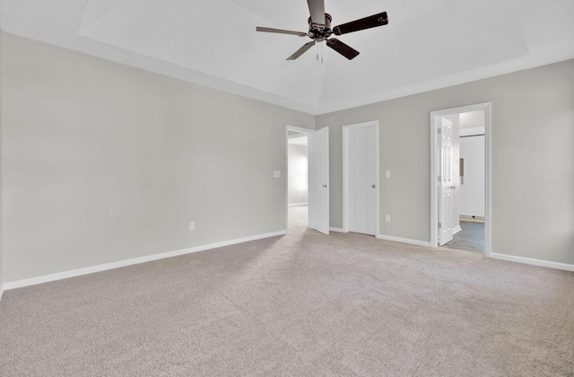 unfurnished bedroom featuring ensuite bathroom, a raised ceiling, and ceiling fan