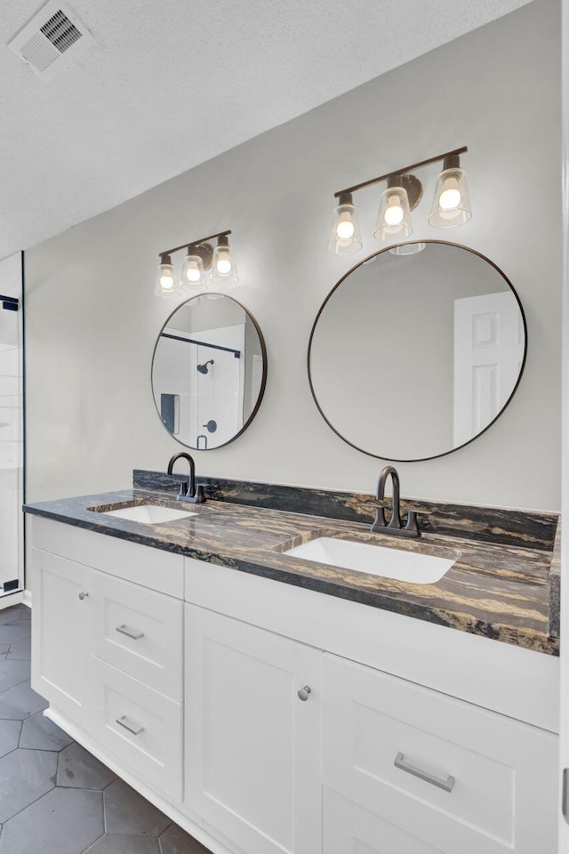 bathroom with tile patterned floors, vanity, and a textured ceiling