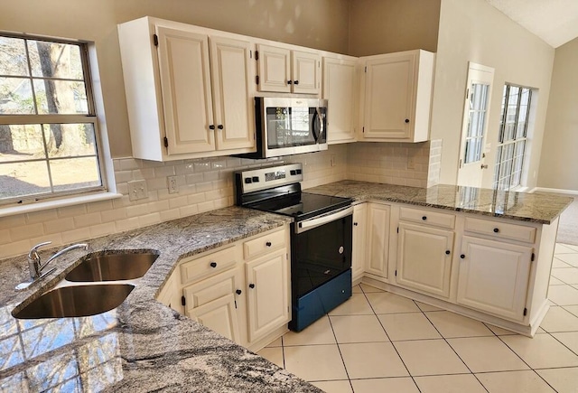 kitchen with sink, vaulted ceiling, light stone countertops, kitchen peninsula, and stainless steel appliances