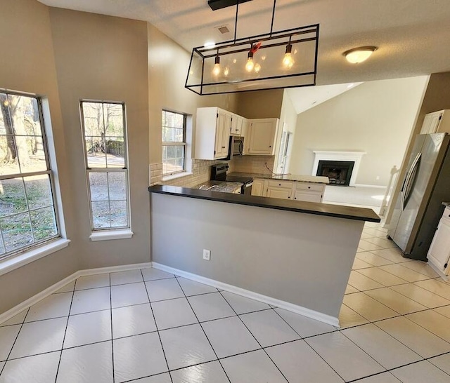 kitchen featuring kitchen peninsula, appliances with stainless steel finishes, backsplash, white cabinetry, and hanging light fixtures