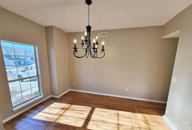 unfurnished dining area with wood-type flooring and an inviting chandelier