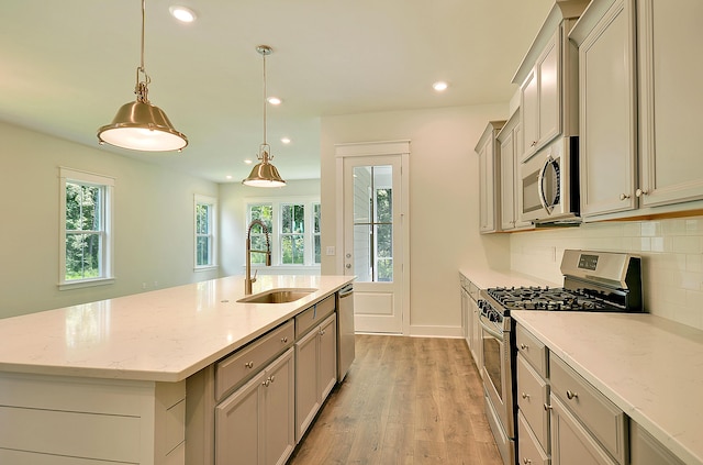 kitchen featuring appliances with stainless steel finishes, a sink, light wood-style floors, recessed lighting, and backsplash