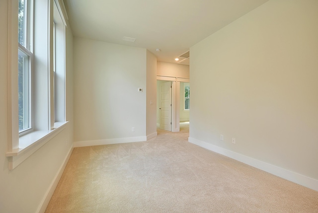 unfurnished room featuring baseboards, plenty of natural light, and light carpet