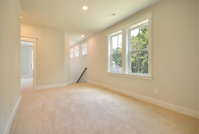 empty room with baseboards, light carpet, recessed lighting, and visible vents