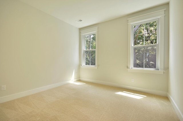 spare room with carpet floors, visible vents, and a healthy amount of sunlight