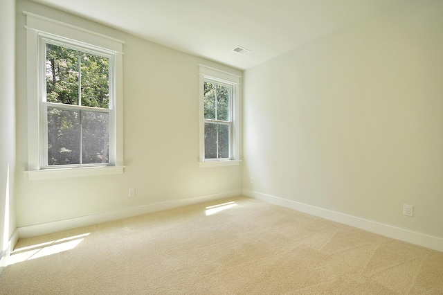 carpeted empty room featuring baseboards, a wealth of natural light, and visible vents