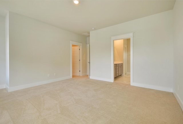 unfurnished bedroom with connected bathroom, baseboards, and light colored carpet