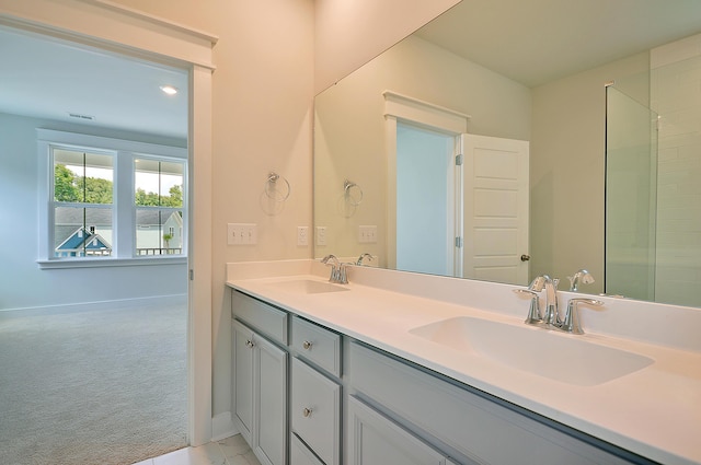 full bath with a sink, baseboards, double vanity, and visible vents