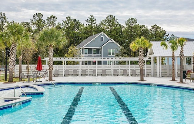community pool with fence, a jacuzzi, and a patio area