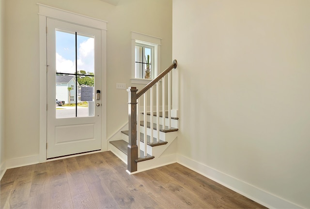 doorway featuring stairs, baseboards, and wood finished floors