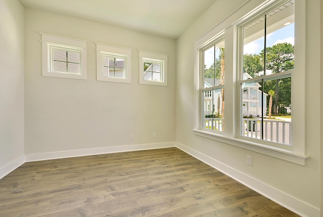 spare room with baseboards, dark wood-style flooring, and a healthy amount of sunlight