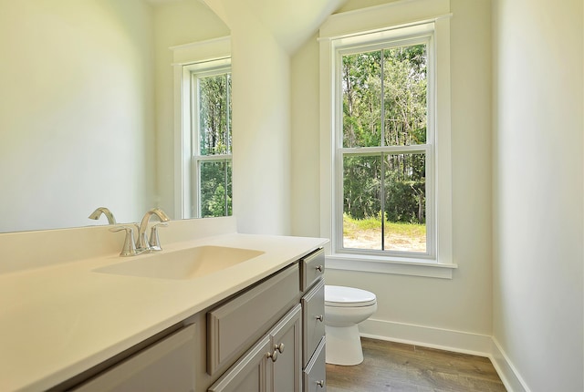 bathroom featuring baseboards, wood finished floors, a healthy amount of sunlight, and toilet