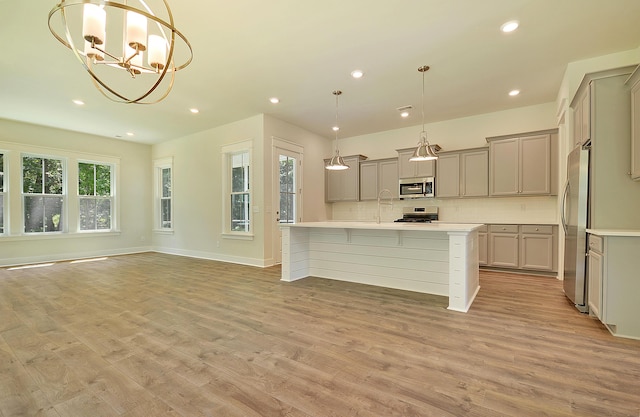 kitchen with an inviting chandelier, gray cabinets, stainless steel appliances, and tasteful backsplash