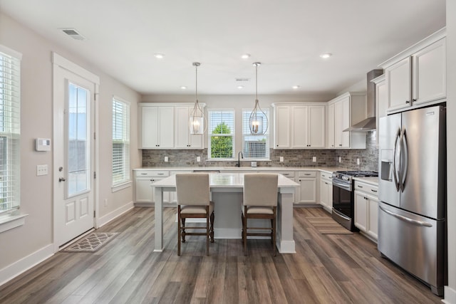 kitchen featuring stainless steel appliances, wall chimney exhaust hood, plenty of natural light, dark wood-type flooring, and recessed lighting
