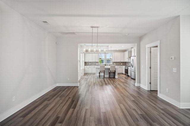 living area with dark wood-type flooring, baseboards, and a chandelier