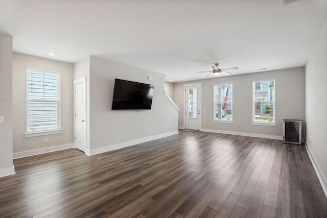 unfurnished living room with healthy amount of natural light, ceiling fan, dark wood finished floors, baseboards, and recessed lighting