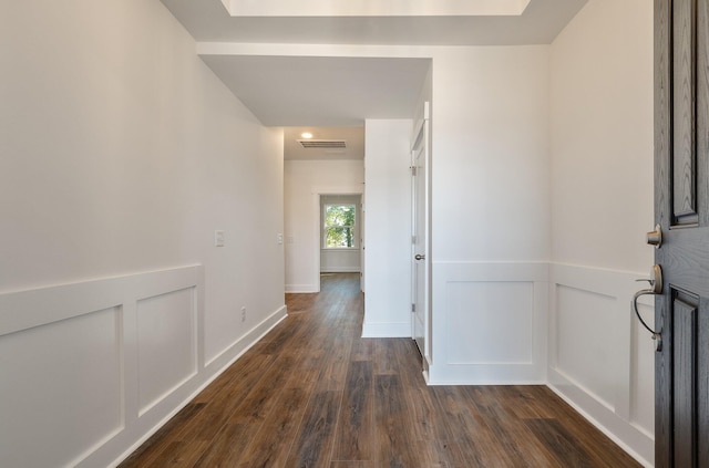 corridor featuring a wainscoted wall, visible vents, dark wood-style floors, and a decorative wall