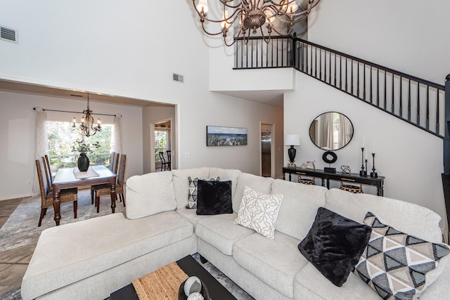 living area featuring visible vents, baseboards, stairway, a high ceiling, and a notable chandelier