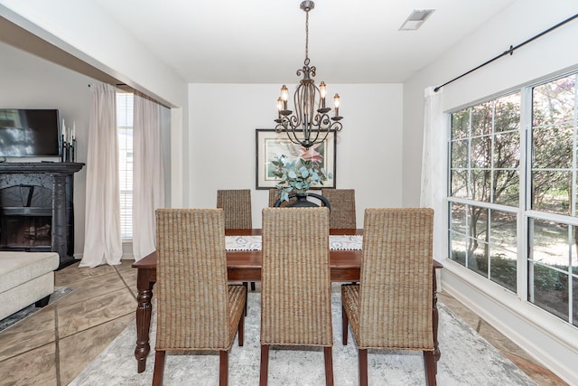 dining space with visible vents, plenty of natural light, a chandelier, and a tiled fireplace