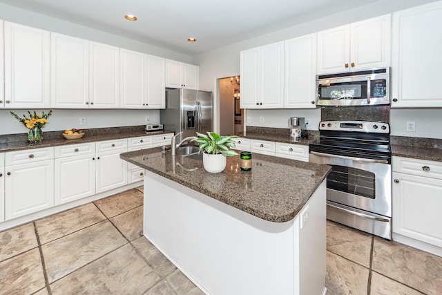 kitchen featuring a center island with sink, dark stone counters, appliances with stainless steel finishes, and white cabinets