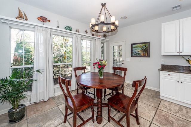 dining space with visible vents, baseboards, stone tile floors, and a chandelier