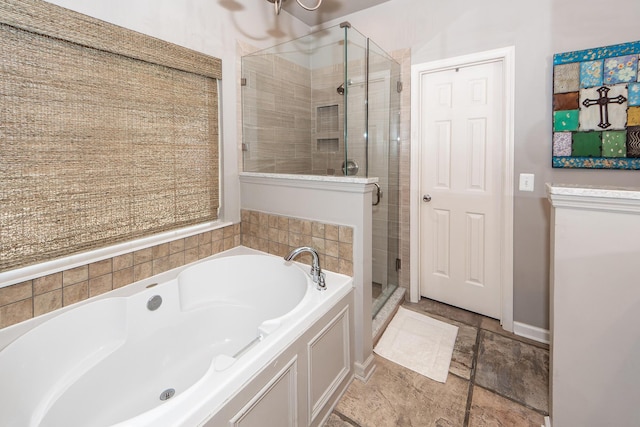 full bath with stone finish flooring, baseboards, a bath, and a shower stall