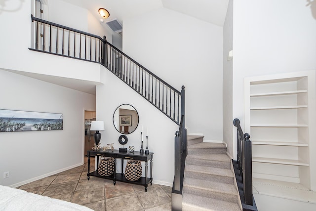 staircase with visible vents, baseboards, high vaulted ceiling, and built in shelves