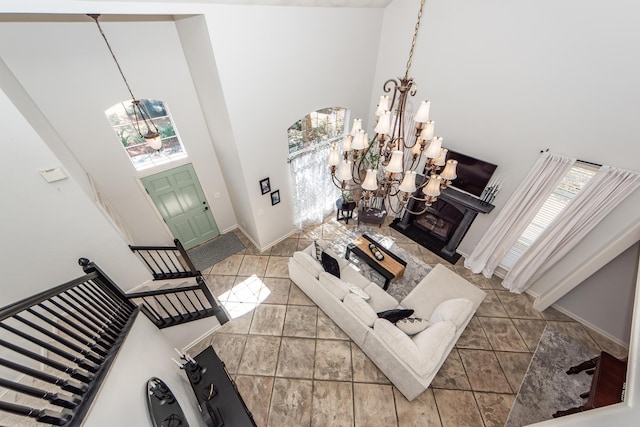 living room featuring stairway, baseboards, an inviting chandelier, and a towering ceiling