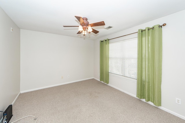 carpeted empty room featuring visible vents, a ceiling fan, and baseboards