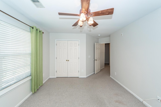 unfurnished bedroom featuring visible vents, a closet, carpet flooring, baseboards, and ceiling fan