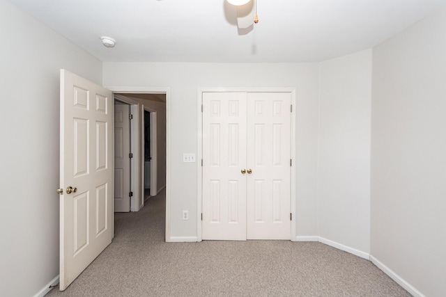 unfurnished bedroom with a closet, light colored carpet, and baseboards