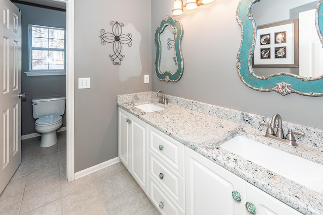 bathroom with tile patterned floors, toilet, baseboards, and a sink