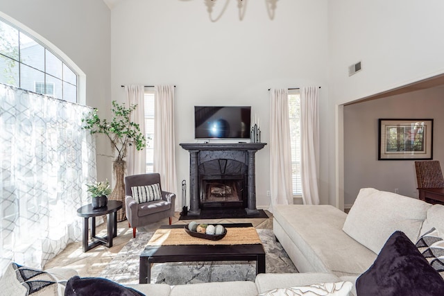 living room with visible vents, plenty of natural light, a fireplace, and a high ceiling