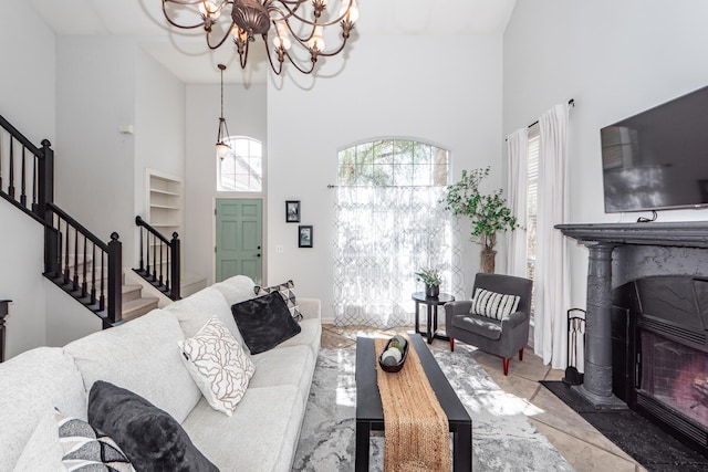 living room with stairway, a high ceiling, and a glass covered fireplace