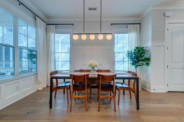 dining room with ornamental molding and light wood-type flooring