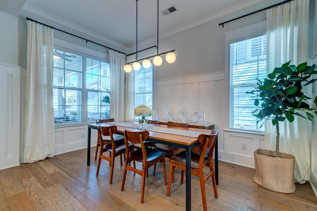 dining room with ornamental molding and light hardwood / wood-style flooring