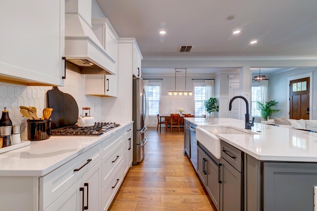 kitchen with hanging light fixtures, premium range hood, appliances with stainless steel finishes, and sink