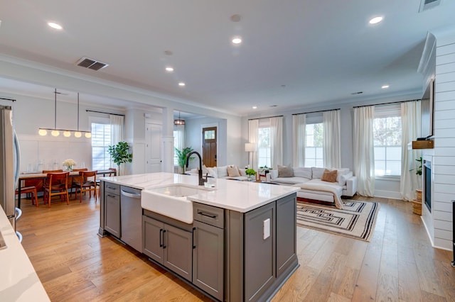 kitchen with sink, light hardwood / wood-style flooring, ornamental molding, gray cabinets, and stainless steel appliances