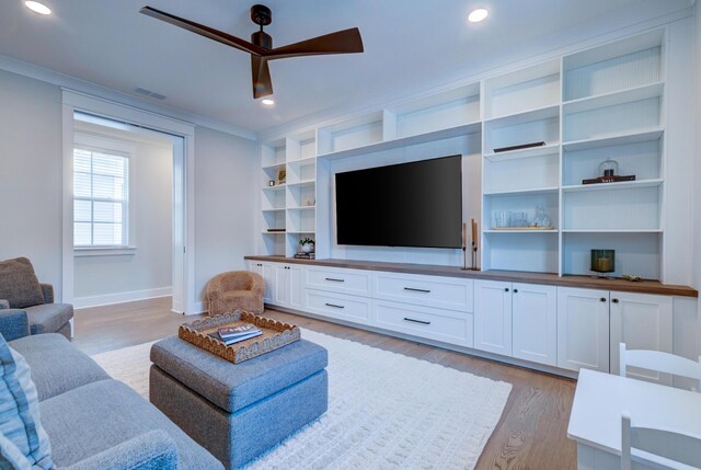 living room with ornamental molding, built in features, ceiling fan, and light hardwood / wood-style flooring