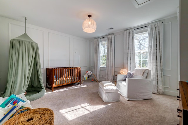 bedroom featuring light colored carpet and a nursery area