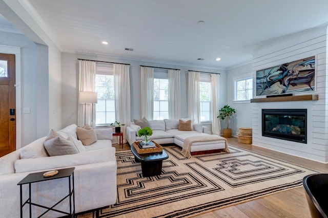 living room with a large fireplace, ornamental molding, and hardwood / wood-style floors