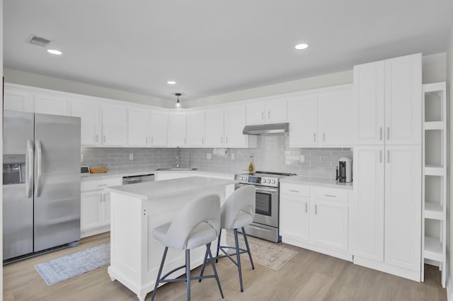 kitchen featuring appliances with stainless steel finishes, light wood-type flooring, a breakfast bar, white cabinets, and a center island