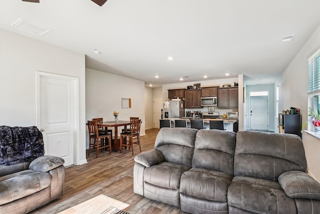 living room featuring a toaster, baseboards, visible vents, recessed lighting, and light wood-style floors