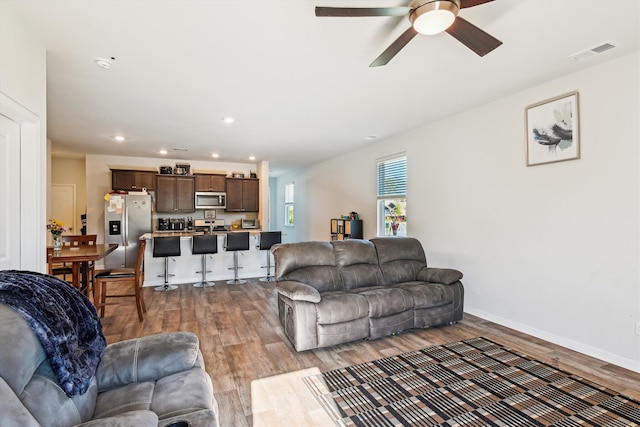 living area featuring light wood-style floors, ceiling fan, baseboards, visible vents, and recessed lighting