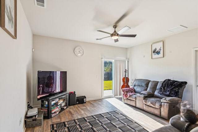 living room with wood finished floors, visible vents, a ceiling fan, and baseboards