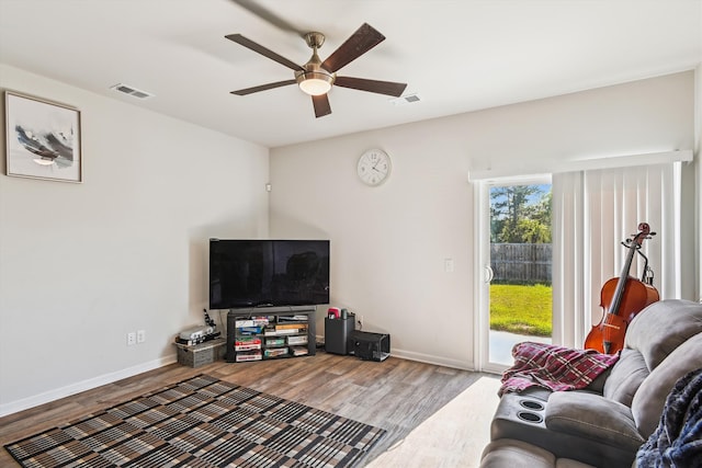living area with baseboards, a ceiling fan, wood finished floors, and visible vents