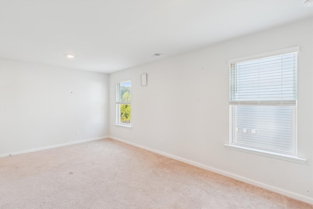 empty room featuring baseboards and light colored carpet