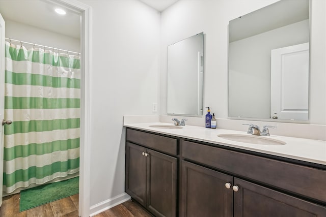 full bath with a shower with shower curtain, double vanity, wood finished floors, and a sink