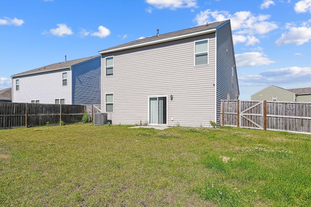 rear view of house featuring a lawn, central AC, and a fenced backyard