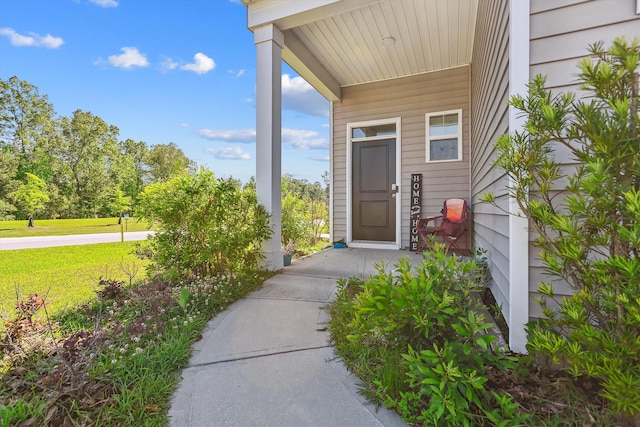 doorway to property featuring a lawn and covered porch